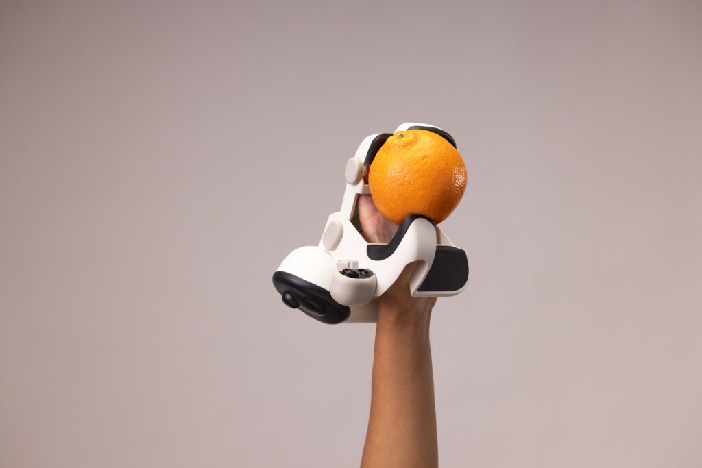 emo robot hand demonstrating fine grip by holding an orange, showing dexterity in everyday objects